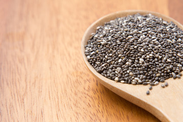 chia seeds (Salvia Hispanica) in a wooden spoon on wooden background