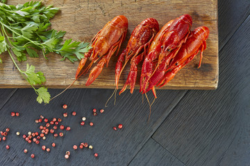 Crayfish with fresh green cilantro. Delicious, boiled, red crawfishes on a dark wooden table, close-up.