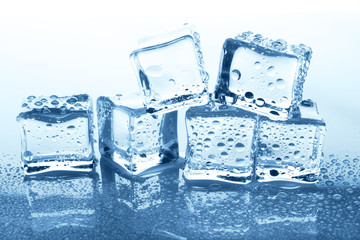 Transparent ice cubes group with reflection on blue glass with water drops