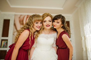 Fototapeta premium Smilling bride with bridesmaids on red dresses indoor room.