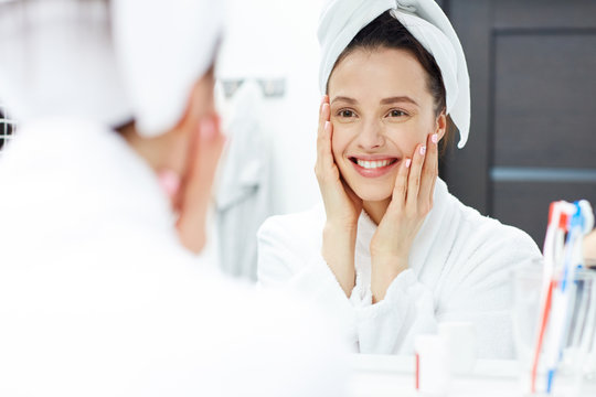 Young Woman In Bathrobe Looking In Bathroom Mirror