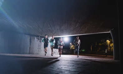 Photo sur Aluminium Jogging Young men and women jogging together at night