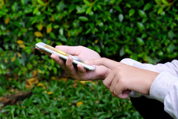 Woman hand using smart phone on green park background