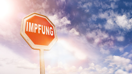 Impfung auf rotem Stoppschild vor blauem Wolkenhimmel