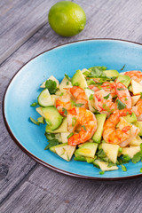 Shrimp, Avocado, Apple and Onion Salad. Grilled prawns on blue plate.