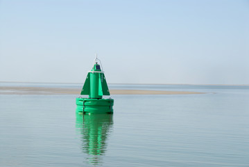 een groene boei op de waddenzee