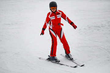 young girl in a red suit skis