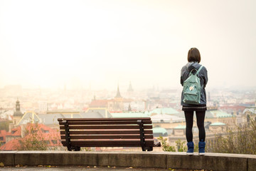 Young japanese girl stay near bench and watching on panorama of Prague.