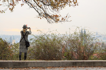 Young women photographs the panorama of Prague her smartphone.