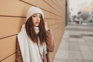 Girl standing near the wall and looking at camera. Blur yellow background