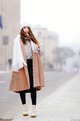 Girl walking near the wall and looking at camera. Blur yellow background