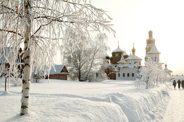 Obraz premium Orthodox monastery behind of bare hoary birch in deep snow