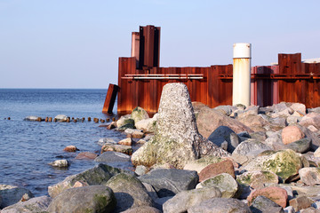 Obraz premium Stones, breakwater and rusty iron wall on the Baltic Sea coast.