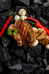 meat grilling on coal background with mushrooms, garlic and red pepper