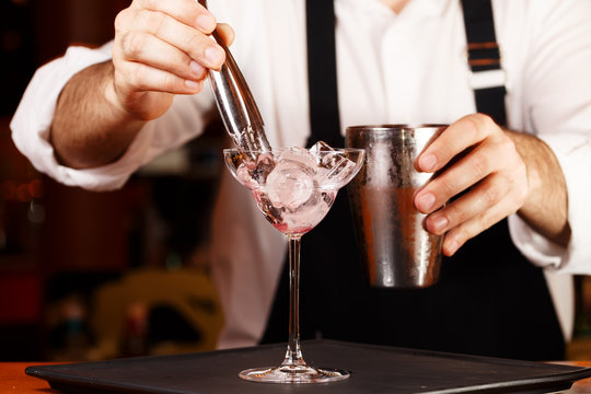 Barman in making cocktail at a nightclub. Nightlife concept. No face. Adding ice to glass
