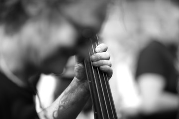 Musician's hand on the fretboard contrabass on a blurred background of the concert participants