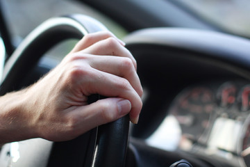 Driver's hand on the steering wheel of a car