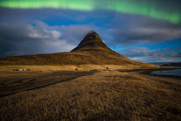 Obraz premium Aurora or the Northern light over the Kirkjufell mountain the iconic famous mountain in triangle shape in the west region of Iceland.