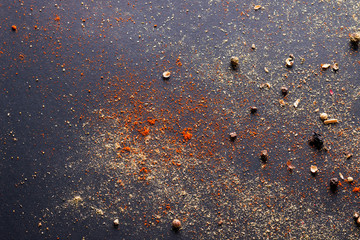 Spicy background with assortment of different hot chili and allspice peppers and mix of other spices on a dark background