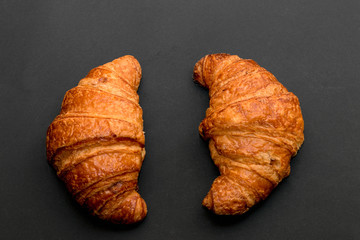 Two fresh croissant on a black slate background. Top view