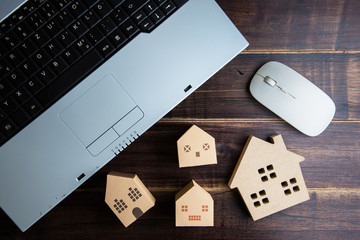 Wooden house, paper house and Laptop note book on wooden table background with copy space.Real estate concept, New house concept, Finance loan business concept.