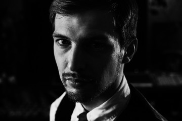 Black and white dramatic portrait of a handsome confident man, 30-35 years old. Strong face looking to the camera, half face in shadow.