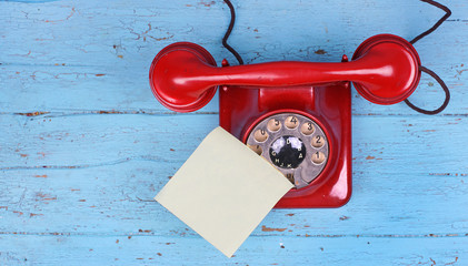 rotes altes Telefon mit Wählscheibe und Klebezettel für Infos