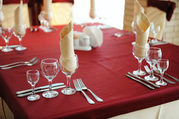 Served table in a restaurant. Cream and maroon colors. Bows drapery on chairs. Close up
