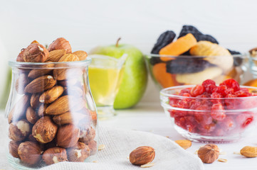 Mix of dried fruits and nuts, almonds, hazelnuts, dried cherries, dried apricots, figs and prunes on white wooden background. Healthy and wholesome food. The concept of natural organic food, diet.