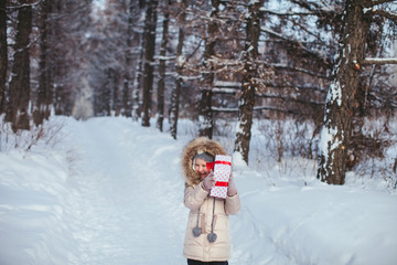 little cheerful girl holding, shaking a box with a gift in a winter forest