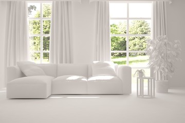 White room with sofa and green landscape in window. Scandinavian interior design