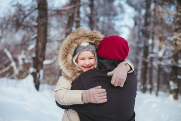 happy little girl hugging her mother in the winter forest