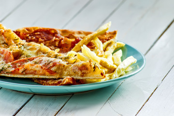 Pizza, French fries on the plate on white wooden background