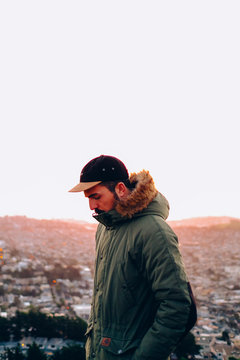 Bearded man in cap and sunglasses on red wall in sunlight