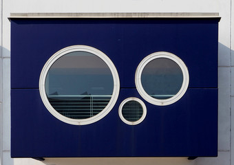Circle windows of different sizes on blue wall background. Abstract modern architecture details
