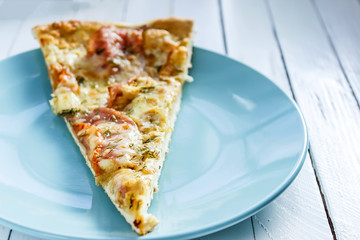 Pizza on a blue plate on a white wooden background