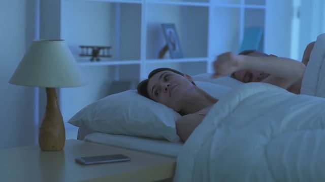The woman phone near the man on the bed. Camera around motion