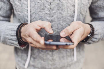 Man wearing sweater using smart phone