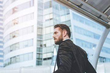 Fototapeta premium Side view of success businessman looking on modern building with copy space