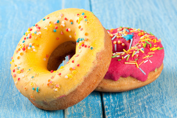 two glazed donut on blue wooden background