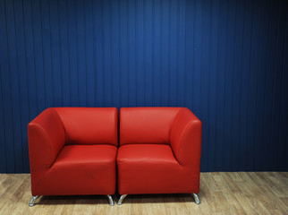 Red leather sofa on a background of blue walls. Texture for the design