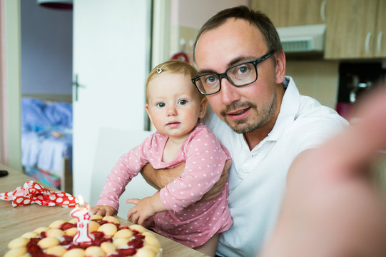 Father with his daughter and birthday cake, taking selfie