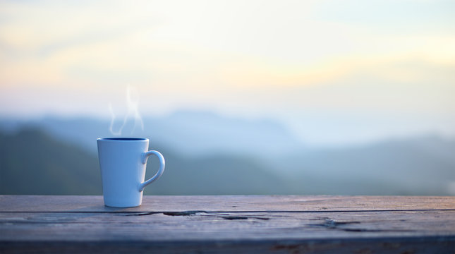 Cup with coffee on table over mountains landscape with sunlight. Beauty nature background..