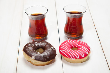 Colorful donuts and two cups of tea on a white table