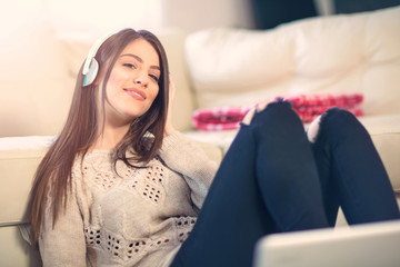 Young woman with headphones listening to music in the living room