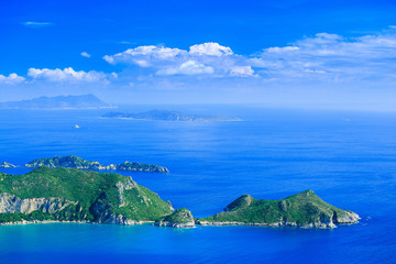 Fototapeta premium Beautiful summertime panoramic seascape. View of the cliff into the crystal clear azure sea bay and distant islands.