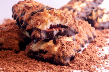 Pile of shortbread cookies with jam and chocolate icing on the scattered cocoa powder