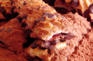 Pile of shortbread cookies with jam and chocolate icing on the scattered cocoa powder
