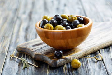 Green and black olives in a wooden bowl.