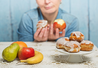 Woman choosing between fruit and sweets